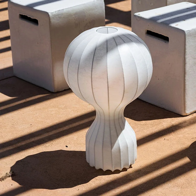 Designerska lampa barcato w białym kolorze o nowoczesnym, unikalnym kształcie na tle betonu