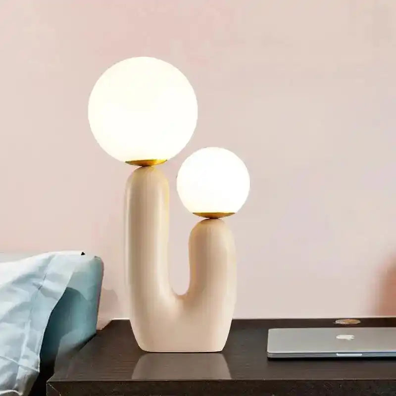 Nowoczesna lampa biurkowa z dwoma białymi kulistymi kloszami na beżowej podstawie