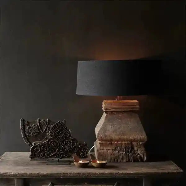 Lampa stołowa z czarnym kloszem i rustykalną podstawą na drewnianym stole