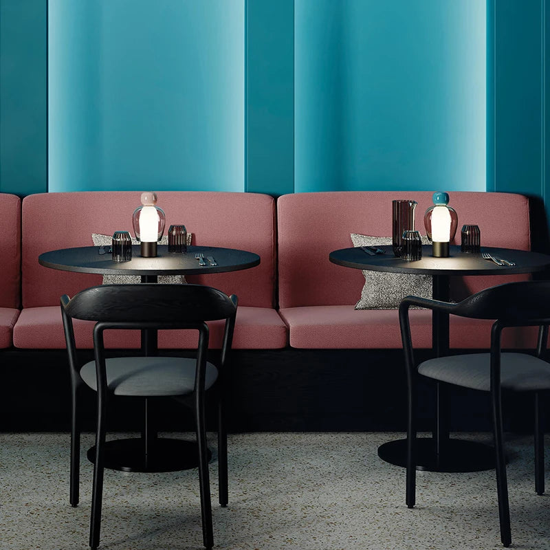 Nowoczesna lampa stołowa ZISIZ na stoliku w stylowej kawiarnianej przestrzeni z różowymi kanapami