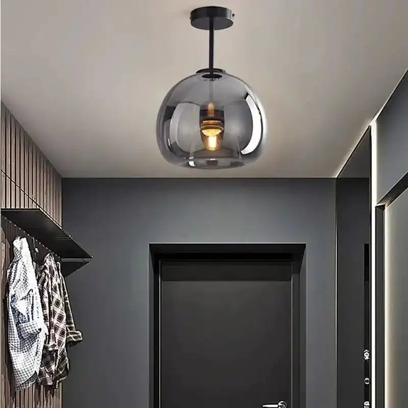Nowoczesna lampa sufitowa z przezroczystym szklanym kloszem w stylowym korytarzu