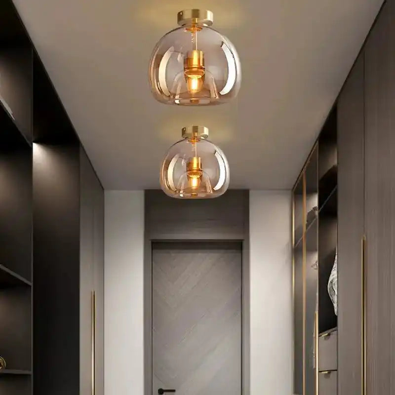 Nowoczesna lampa sufitowa z przezroczystym kloszem i złotymi detalami w przedpokoju