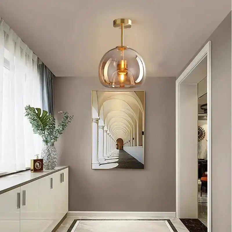 Nowoczesna lampa sufitowa ze szklanym kloszem i złotym wykończeniem w eleganckim wnętrzu