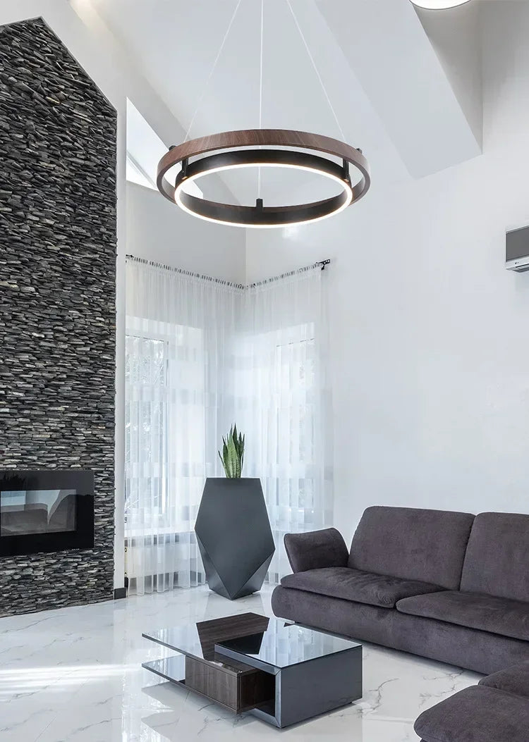 Nowoczesny żyrandol do salonu w stylu minimalistycznym, zawieszony w jasnym wnętrzu z kamienną ścianą