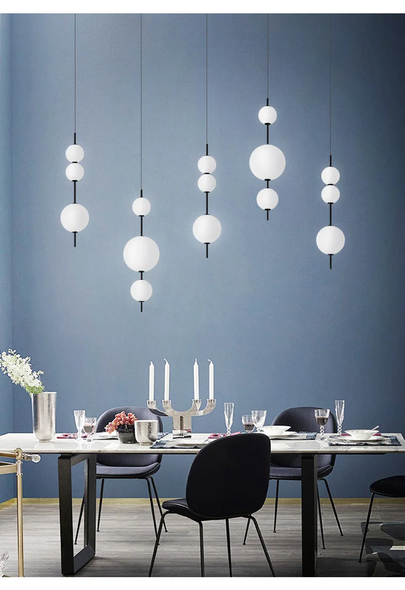Eleganckie lampy kule wiszące nad stołem w nowoczesnej jadalni z niebieską ścianą