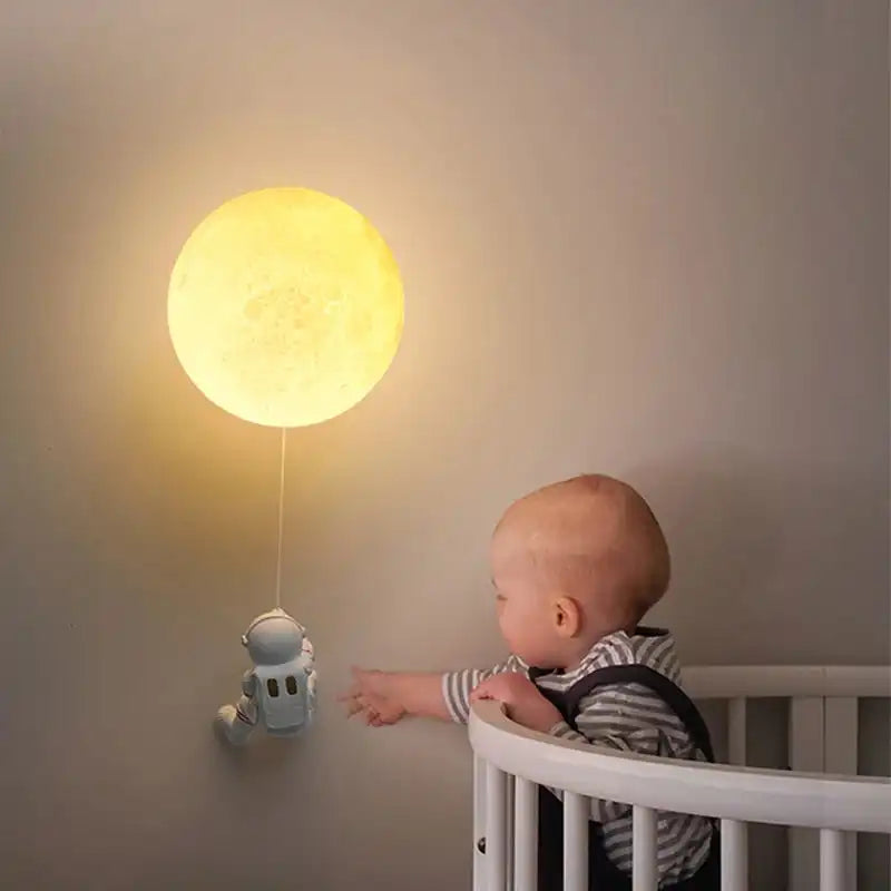 Lampka nocna oświetlenie LED Astrae w kształcie astronauty i księżyca przy łóżeczku dziecięcym