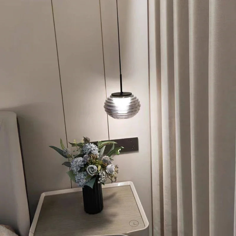 Designerska lampa do sypialni w stylu nowoczesnym wisząca nad stolikiem nocnym z kwiatami