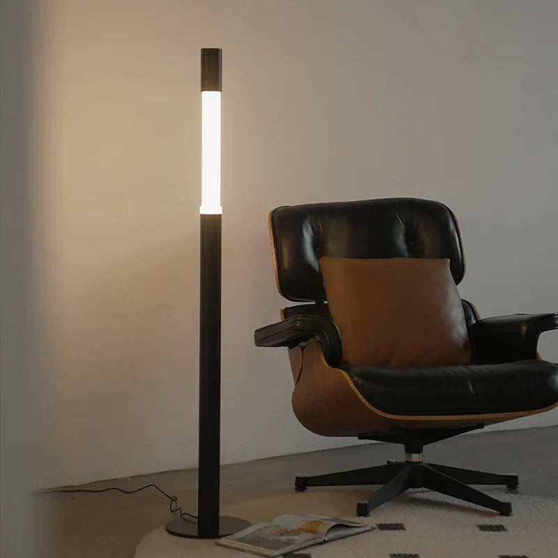 Designerska lampa podłogowa CHUBAN obok czarno-brązowego fotela w nowoczesnym wnętrzu