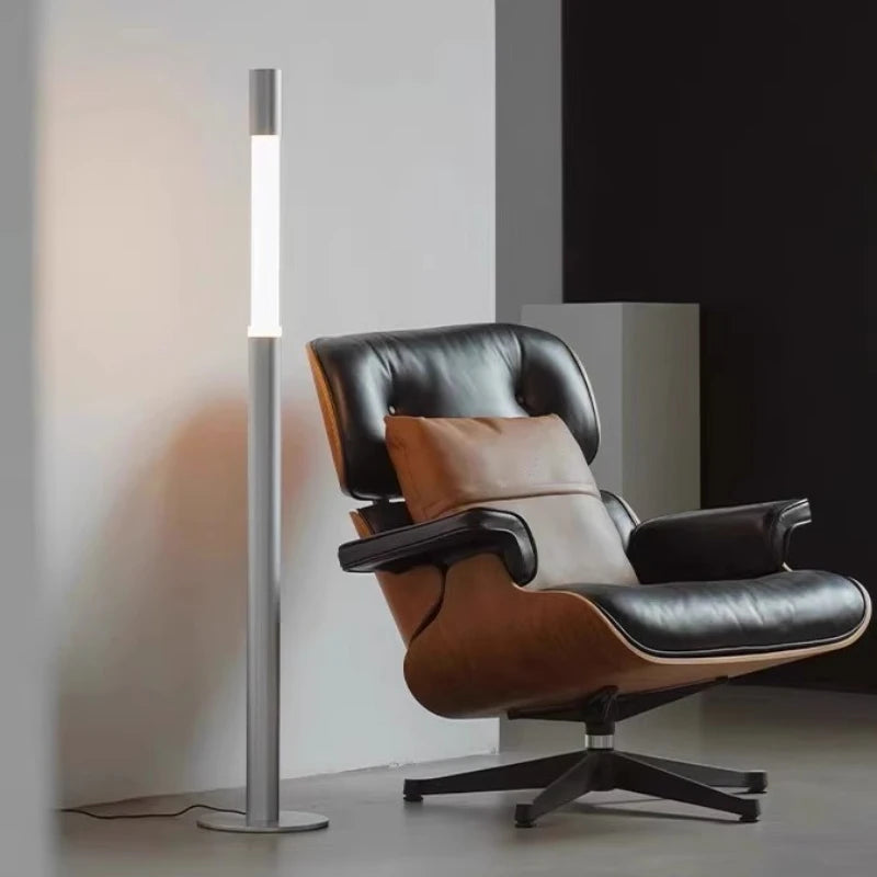 Designerska lampa podłogowa CHUBAN obok nowoczesnego fotela skórzanego w salonie
