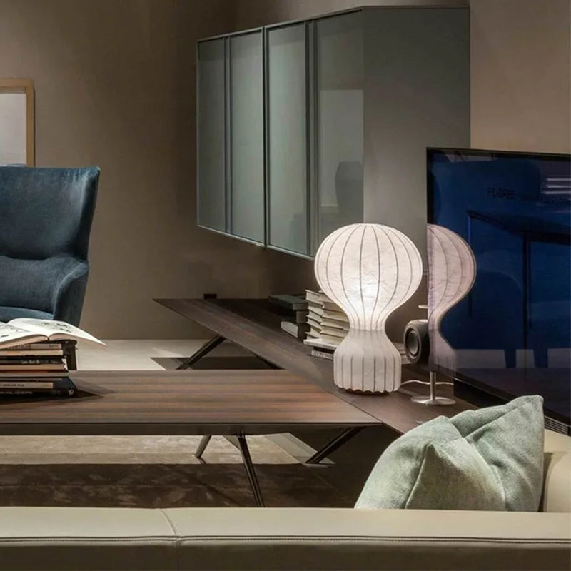 Designerska lampa barcato w nowoczesnym salonie na drewnianym stoliku obok telewizora