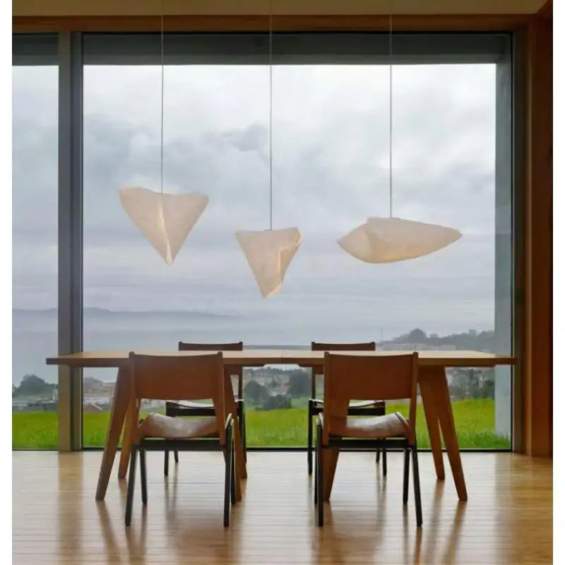 Nowoczesna designerska lampa wisząca w kształcie liści nad drewnianym stołem z widokiem na wodę