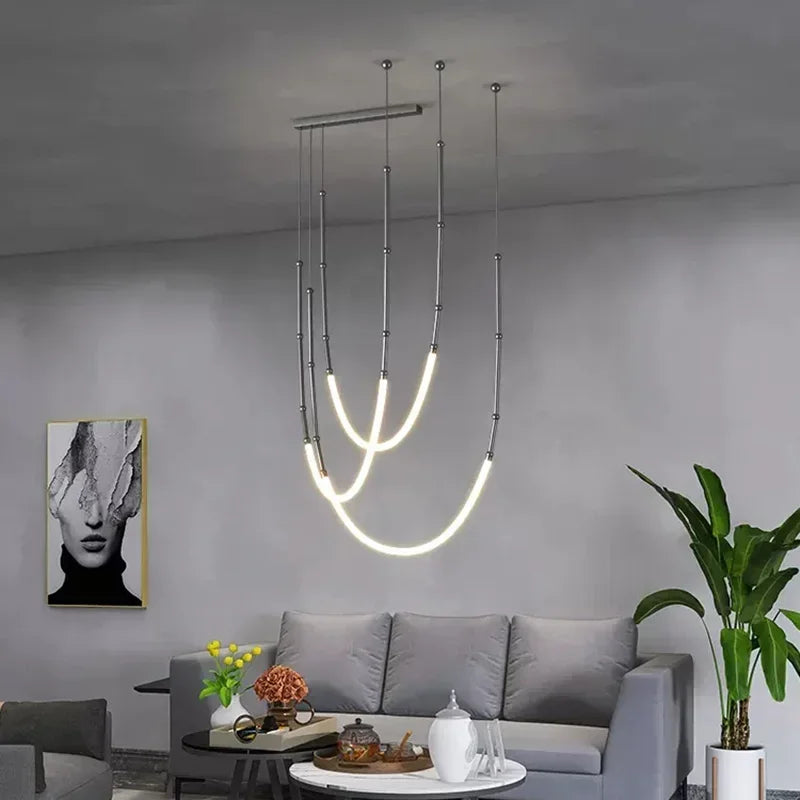 Nowoczesny żyrandol marki xiuxiu z LED w minimalistycznym salonie z szarą sofą i rośliną