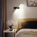 Nowoczesny kinkiet ASCELINA oświetlający sypialnię nad stolikiem z kwiatami