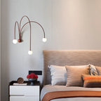 Kinkiet JIANKEXING z trzema kulistymi żarówkami nad stolikiem nocnym w nowoczesnej sypialni