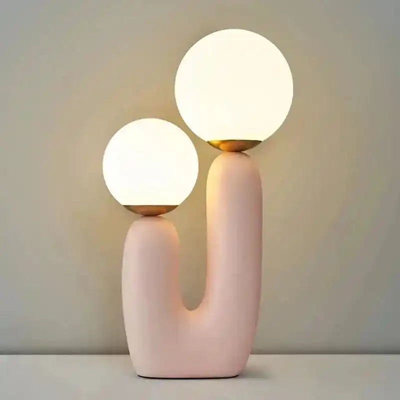 Nowoczesna różowa lampa biurkowa z dwoma szklanymi kulistymi kloszami na białym tle