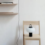 Lampa biurkowa SANDYHA w nowoczesnym stylu na drewnianym krześle w jasnym pomieszczeniu