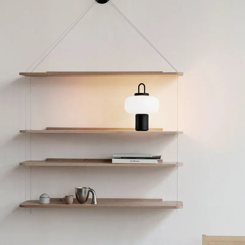Nowoczesna lampa biurkowa SANDYHA z mlecznym kloszem i czarną podstawą na drewnianej półce