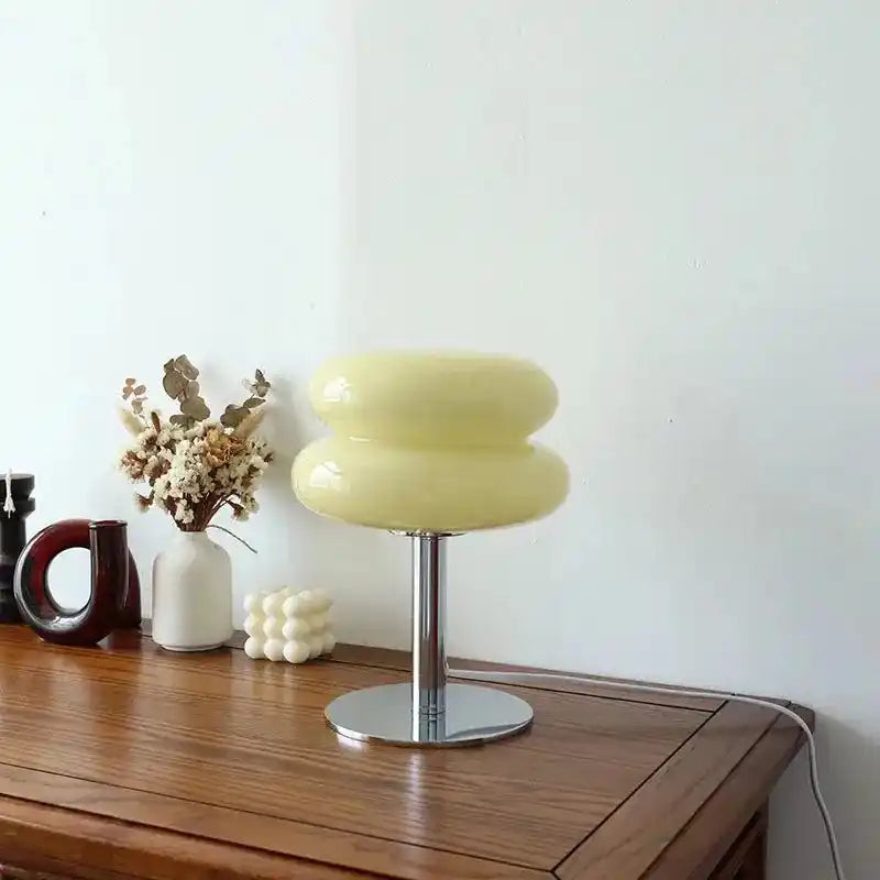 Żółta lampa biurkowa yueyi z chromowaną podstawą na drewnianym biurku z dekoracjami