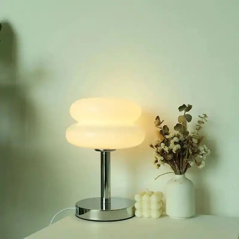 Lampa biurkowa yueyi z mlecznym, owalnym kloszem i metalową podstawą na białym stole