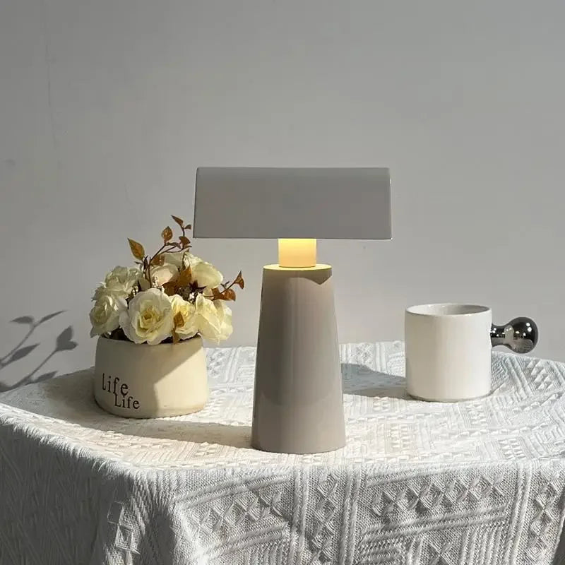 Nowoczesna lampa do biura JIANKEXING o minimalistycznym designie ustawiona na stole z dekoracyjnymi kwiatami