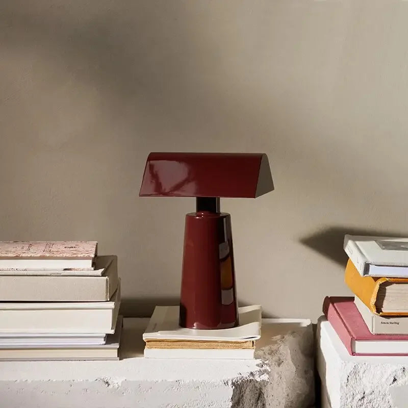 Nowoczesna czerwona lampa do biura JIANKEXING ustawiona na stosie książek