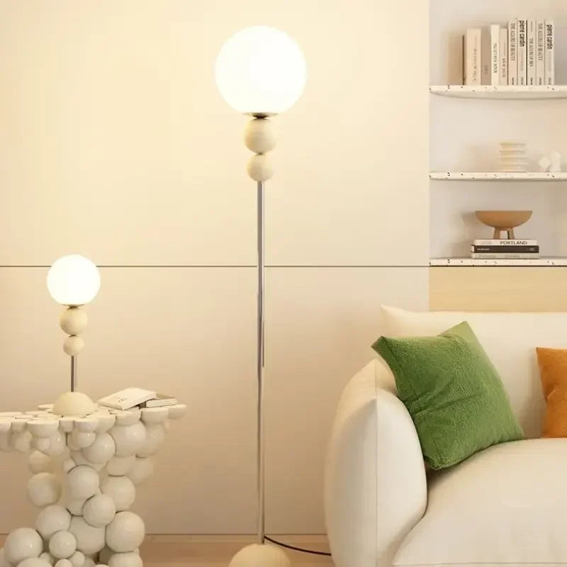 Elegancka lampa podłogowa SANDYHA z kulistym białym kloszem w nowoczesnym salonie
