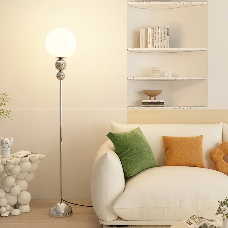 SANDYHA lampa podłogowa ze szklaną kulą i metalową podstawą w nowoczesnym salonie
