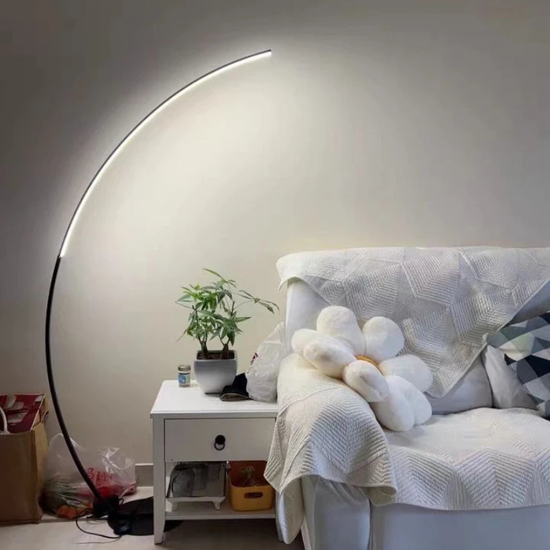 Nowoczesna lampa podłogowa SANDYHA z zakrzywionym ramieniem obok białej sofy