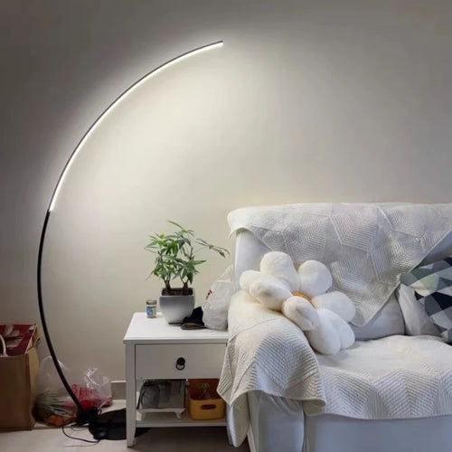 Nowoczesna lampa podłogowa SANDYHA z zakrzywionym ramieniem obok białej sofy