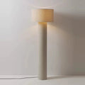 Nowoczesna lampa podłogowa z cylindryczną podstawą i jasnym abażurem na neutralnym tle