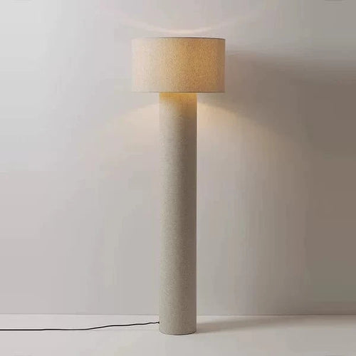 Nowoczesna lampa podłogowa z cylindryczną podstawą i jasnym abażurem na neutralnym tle