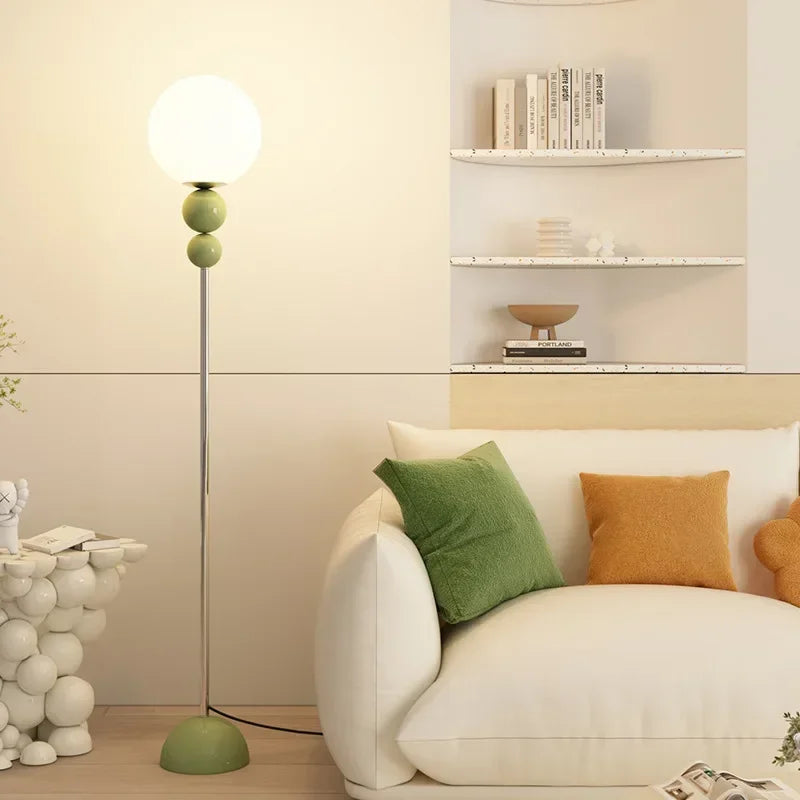 SANDYHA nowoczesna zielona lampa podłogowa z kulistym kloszem nad białą sofą w salonie