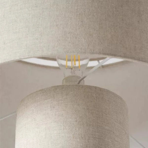 Beżowa lampa podłogowa z tekstylnym abażurem i widoczną żarówką LED