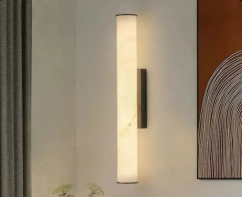 Nowoczesna lampa ścienna w kształcie smukłego walca emitująca ciepłe światło na szarej ścianie