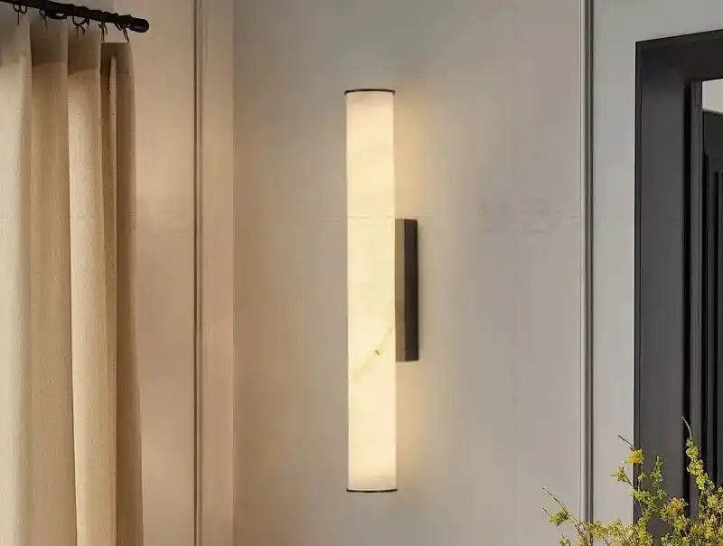 Nowoczesna lampa ścienna w kształcie pionowego walca zamontowana na jasnej ścianie w salonie