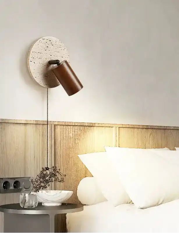 Minimalistyczna lampa ścienna z brązowym kloszem i marmurową podstawą nad nocnym stolikiem