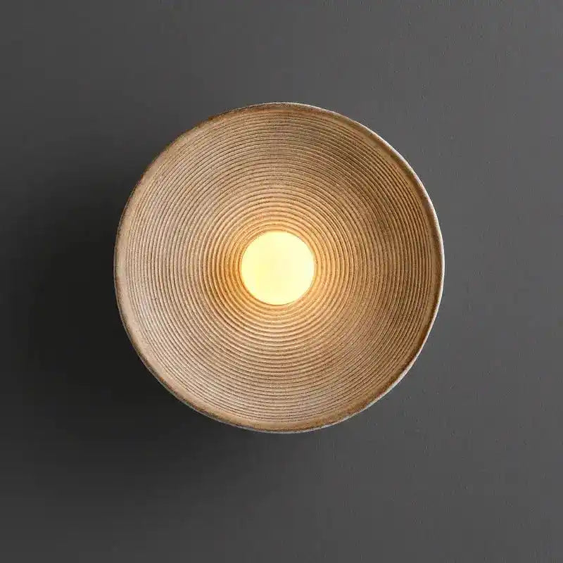 Nowoczesna lampa ścienna QUASHION z okrągłym geometrycznym wzorem oświetlająca szarą ścianę
