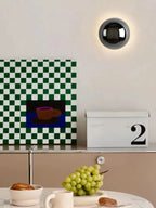 Lampa scienna z czarną kulistą oprawą oświetlająca ścianę nad kuchennym blatem