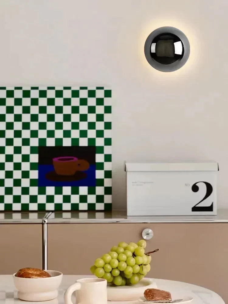 Lampa scienna z czarną kulistą oprawą oświetlająca ścianę nad kuchennym blatem