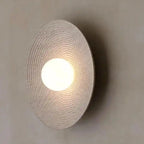 QUASHION lampa ścienna z okrągłym abażurem i ciepłym światłem na neutralnej ścianie