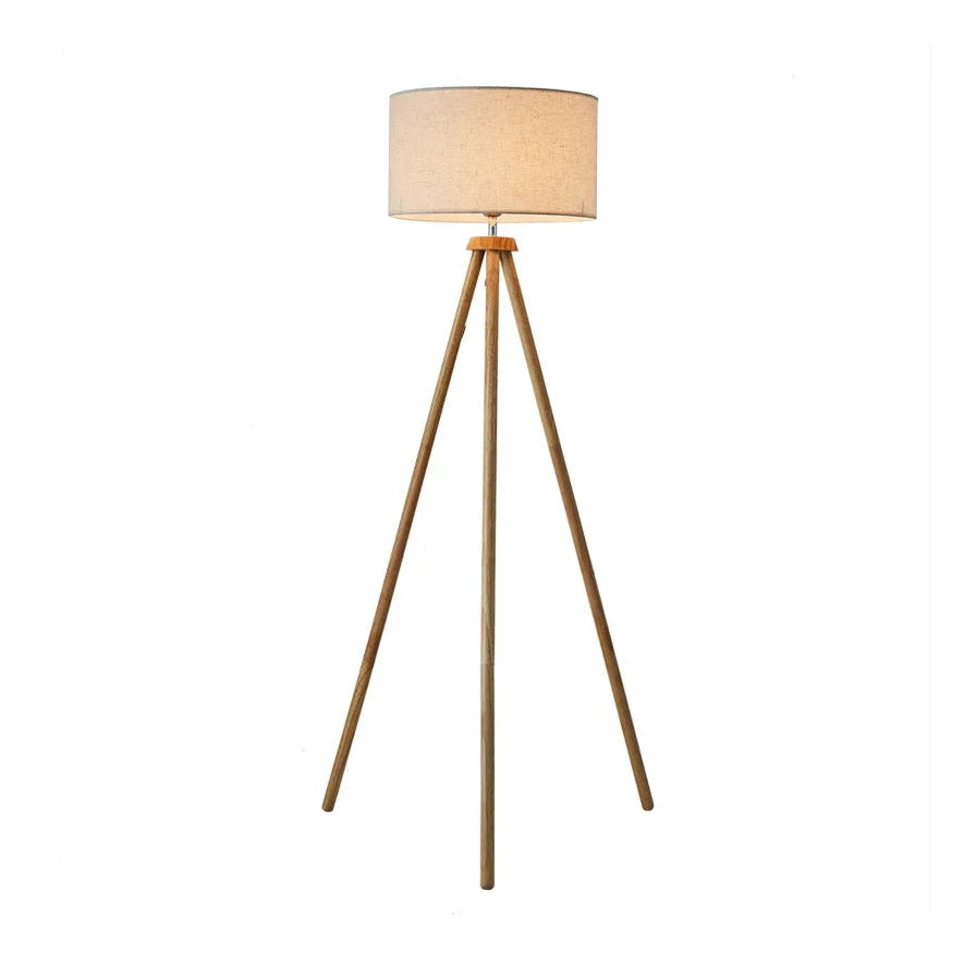 Elegancka lampa stojąca do salonu z drewnianą podstawą na trzech nogach i jasnym abażurem