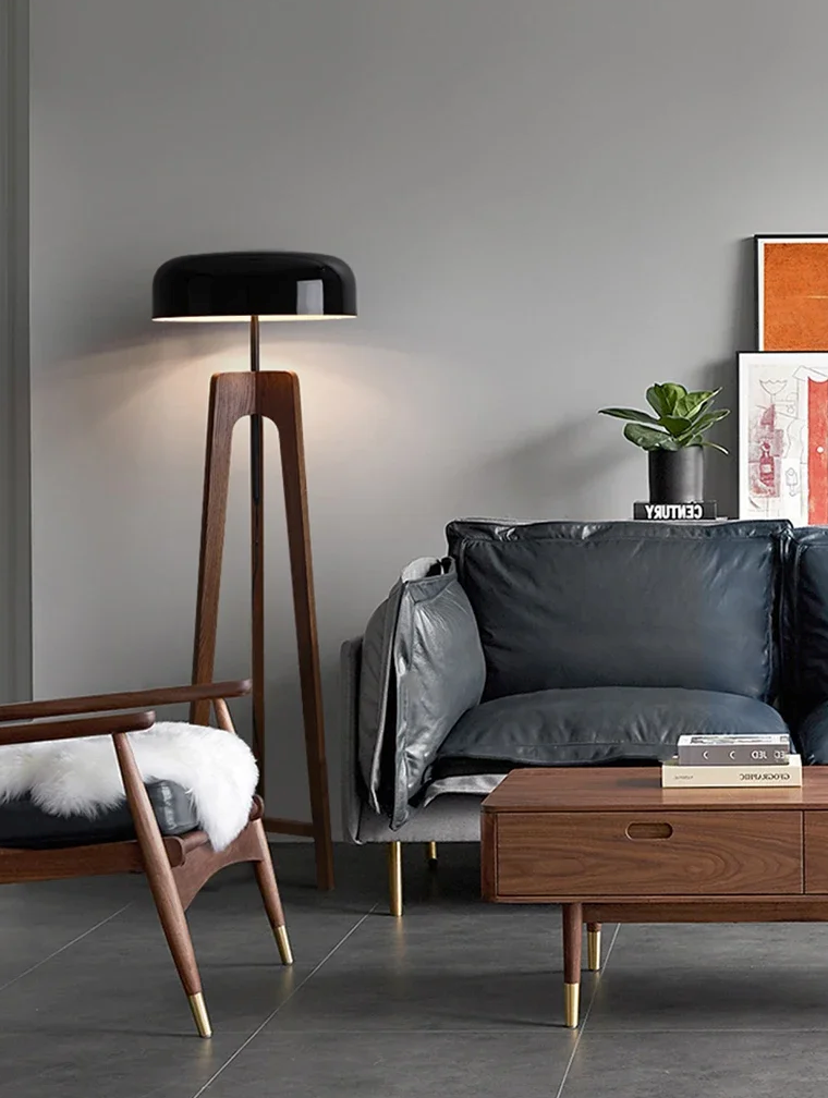 Nowoczesna czarna lampa stojąca SANDYHA z drewnianą podstawą w salonie z szarą sofą i drewnianymi meblami