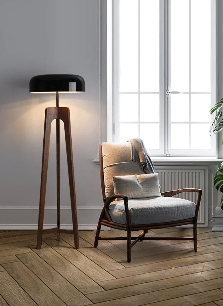Lampa stojąca SANDYHA z drewnianą podstawą i czarnym kloszem obok fotela w nowoczesnym salonie