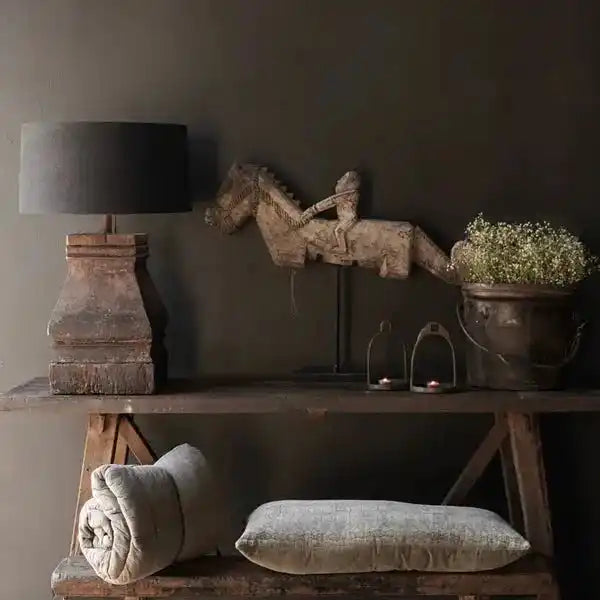 Lampa stołowa z czarnym abażurem na drewnianej podstawie na rustykalnym stoliku z dekoracjami