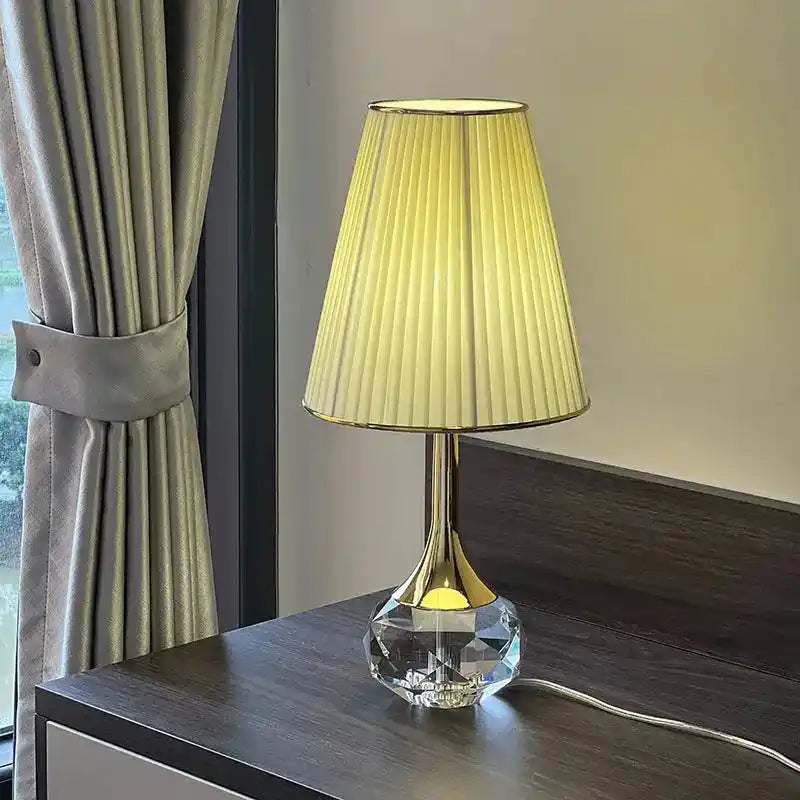 Lampa stołowa Moss z eleganckim plisowanym abażurem i kryształową podstawą na ciemnym blacie