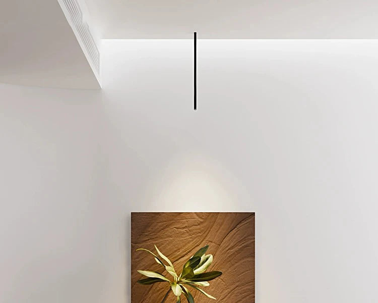 Nowoczesna czarna lampa sufitowa wisząca nad obrazem w minimalistycznym wnętrzu