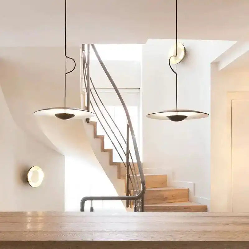 Nowoczesna lampa sufitowa do salonu wisząca na czarnych przewodach nad drewnianym stołem w minimalistycznym wnętrzu