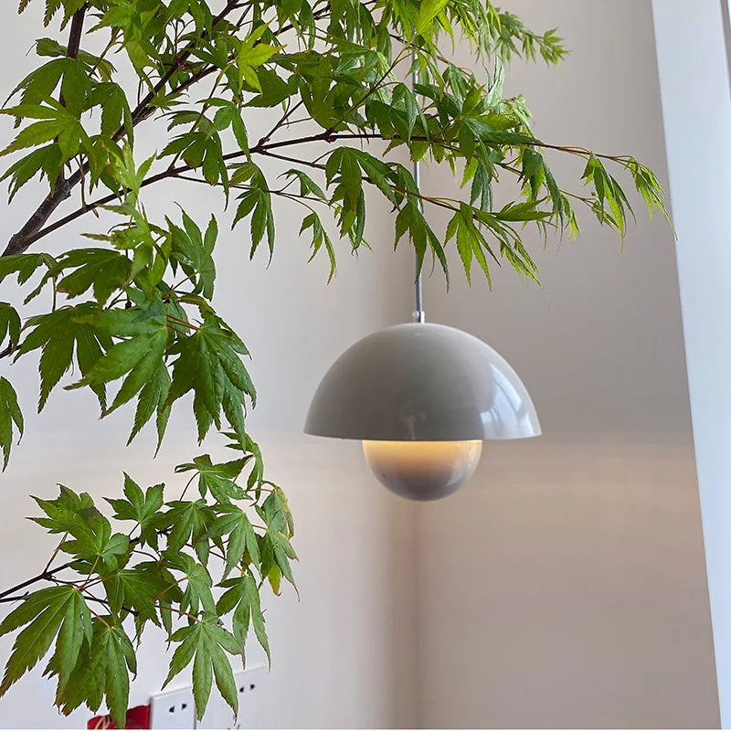 Stylowa lampa sufitowa w szarym kolorze, zawieszona w nowoczesnym wnętrzu z roślinnością