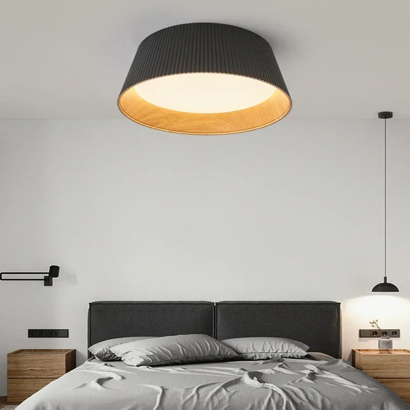 Lampa sufitowa z czarnym abażurem i drewnianym wnętrzem nad łóżkiem w nowoczesnej sypialni