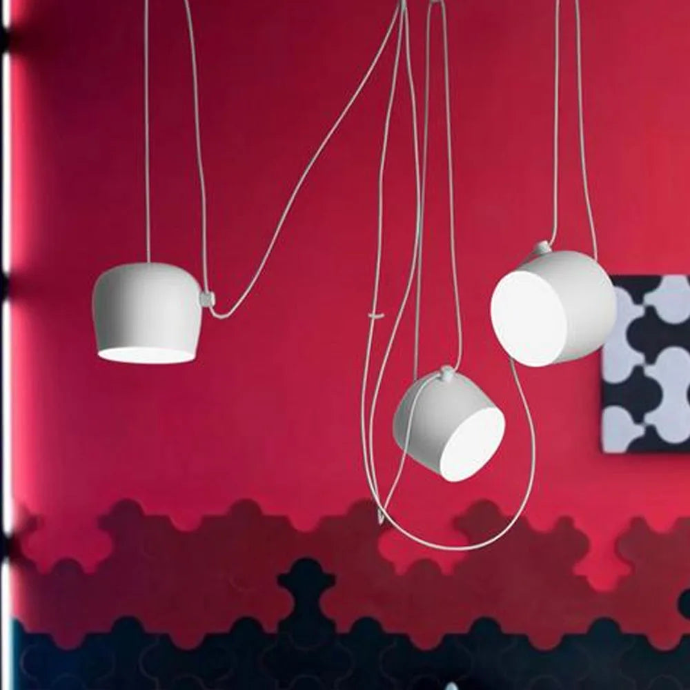 Nowoczesna biała lampa wisząca Lux&vitae na tle czerwonej ściany w salonie